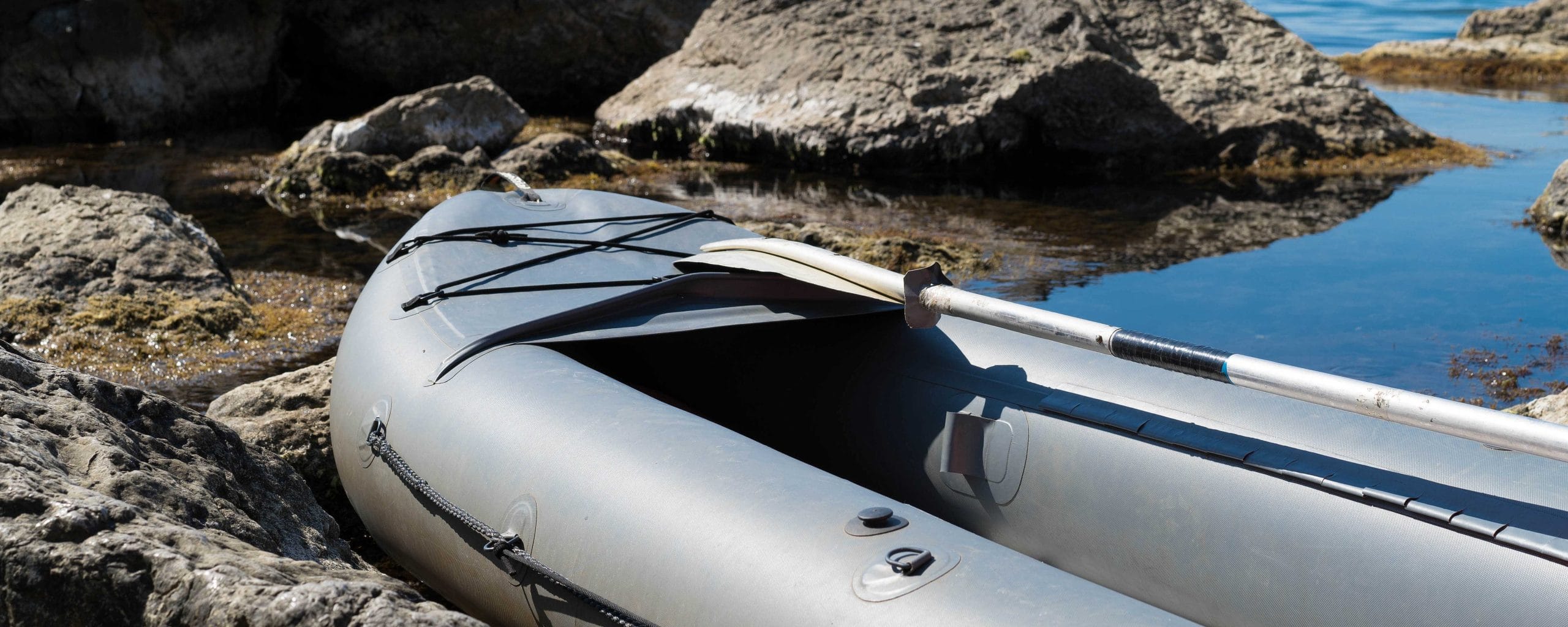 Inflatable canoe among rock formations in the sea. KayakWest Kayak